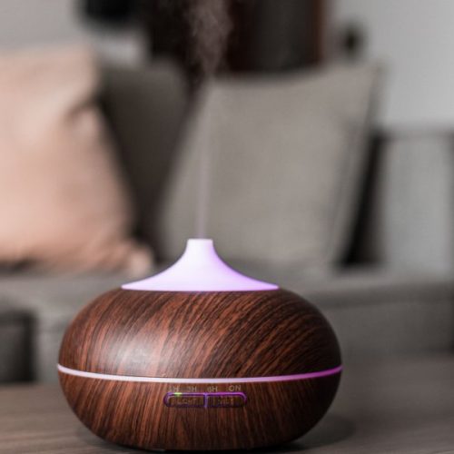 Contemporary smart humidifier on table emitting water vapor and moisturizing air in cozy room