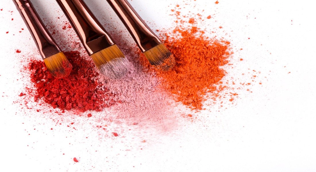 Beauty brands for Black women include makeup brushes with blush or eyeshadow in pink, red and coral tones for Black skin