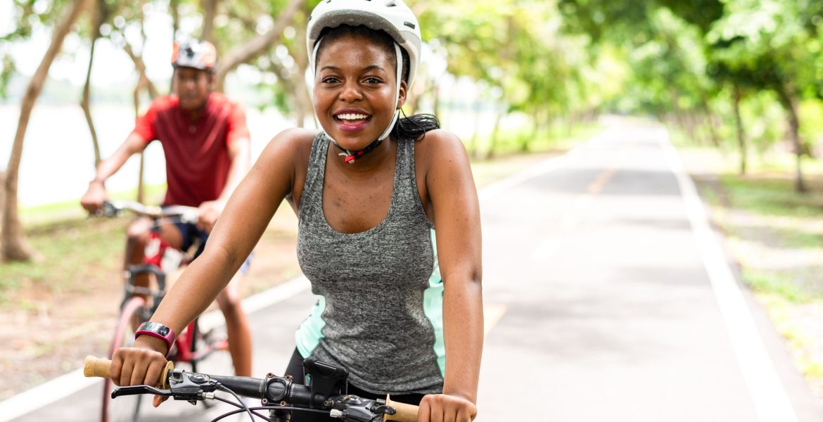 Smiling young Black couple cycling on a clear day for outdoor fitness.