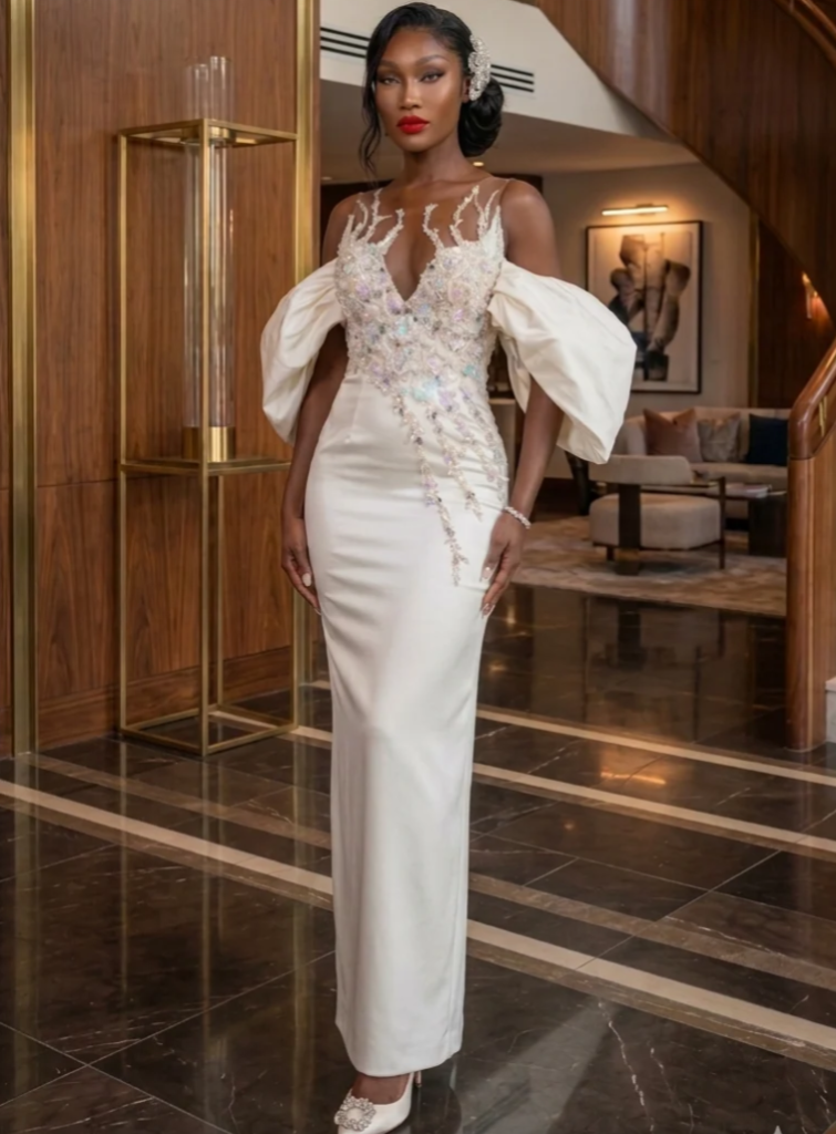 The Ethereal Blossom Gown by Ugochi Iwuaba is designed for the bride who understands that elegance does not need excess to leave an impression. Cut in a sleek sculpted silhouette, this gown is adorned with luminous crystal embellishments that trace the bodice with deliberate artistry, creating a soft illusion of movement and light.